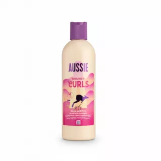 Aussie Bouncy Curls Shampoo bottle with purple cap and pink label held in hand