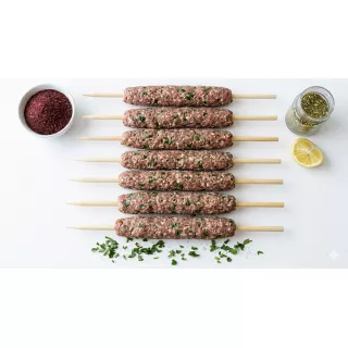 Fresh raw lamb kofta kebabs on wooden skewers with herbs and sesame seeds, accompanied by lemon and spices
