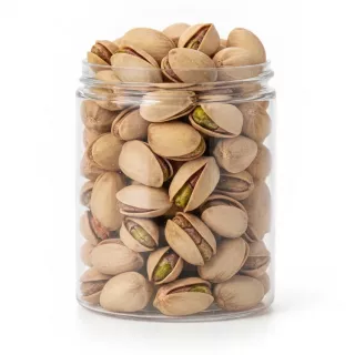 Close-up of salted pistachios in shells inside a clear container