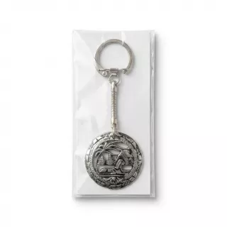 Enhanced Hand holding a silver keyring with palm tree and building motif in packaging