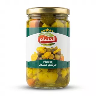 A 1:1 professional e-commerce product photograph featuring a centered glass jar of Al Hussam Mixed Pickles, filling 85% of the frame against a clean white background. The jar has a gold lid and a green and white label with Arabic and English text and an image of the pickles inside. The transparent glass reveals varied pickled vegetables like cauliflower, cucumbers, and carrots in brine. The product is illuminated with professional studio lighting and has a soft, even shadow beneath it.