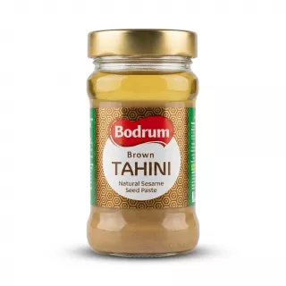Enhanced Hand holding a jar of Bodrum Brown Tahini with front label visible