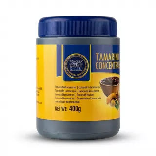 A 400g jar of Heera Tamarind Concentrate with a yellow and blue label, featuring a bowl of the concentrate and a tamarind pod illustration. The product details and weight are clearly visible against a white background with a soft, symmetrical shadow.