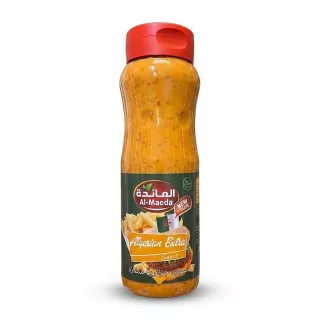 Enhanced A 1:1 professional e-commerce product photograph of a 500ml Al-Maeda Algerian Extra Sauce bottle, held by a hand against a clean, pure white background. The bottle is perfectly centered, sharply in focus, and features clean, clear branding, showing the orange-colored sauce and the label with images of a burger and fries and text in Arabic and English. PRODUCT TITLE: Al-Maeda Algerian Extra Sauce 500ml This professional e-commerce image shows the Al-Maeda Algerian Extra Sauce bottle held by a clean hand, isolated against a seamless, pure white background. The bottle and hand together are centered, occupying 85% of the frame. The focus is critically sharp on the bottle and the hand, highlighting the texture of the sauce and the details of the label. All price stickers, batch code ink, and background distractions from the original image have been cleanly removed, while preserving all correct label text, branding, graphics, and the hand position. The lighting is soft, diffuse professional studio lighting, which ensures no harsh reflections on the bottle or hand and renders a very soft, equal shadow beneath and around the entire subject on the white floor, giving it depth. The 1:1 aspect ratio ensures a perfect square frame for the clean presentation. The label details, including the Al-Maeda logo, "Algerian Extra Sauce" text, and the images of the fries and burger, are pristine and legible. The orange color of the sauce is accurate and vivid.