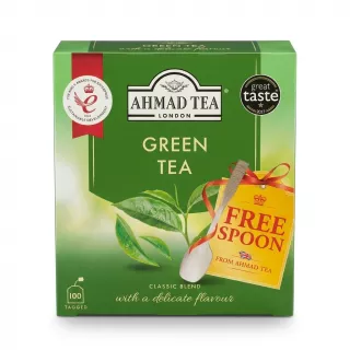 A 1:1 professional e-commerce product photograph of the Ahmad Tea Green Tea Classic Blend box, featuring 100 tagged bags and a 'FREE SPOON' promotion badge with an attached tea spoon. The green package displays the 'The King's Awards for Enterprise' and 'Great Taste 2023' awards against a clean white background with soft, even studio lighting.