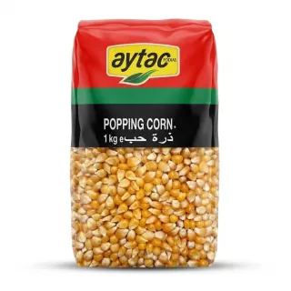 A 1kg bag of Aytac Premium Popping Corn, featuring the brand's logo, English text, and Arabic script against a vibrant red, yellow, and green package, with a clear window revealing the dried corn kernels inside.