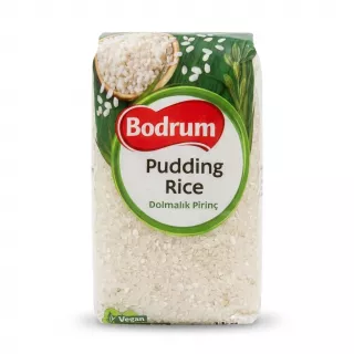 A 1kg package of Bodrum Pudding Rice, specifically labeled 'Dolmalık Pirinç', is shown in a clean, professional photo. The packaging features a clear window at the bottom revealing the uncooked short-grain rice, and includes green leaves, a bowl of cooked rice, and the Bodrum brand logo. PRODUCT TITLE: Bodrum Pudding Rice - Halal, Gluten-Free 1kg