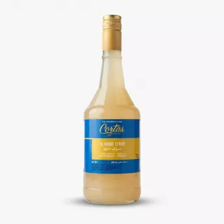 Enhanced Front view of Cortas Almond Syrup 600ml bottle held in a grocery store aisle