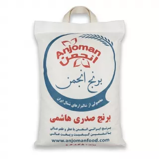 A centered, front-view professional studio photograph of a 5kg fabric bag of Anjoman Sadri Hashemi Rice. The white fabric bag features the 'Anjoman' logo in red within a circular motif, the product name in large blue and red Persian script ('برنج انجمن' and 'برنج صدری هاشمی'), descriptive Persian text regarding quality and origin, and the website 'www.anjomanfood.com'. The bag has a woven handle and sits on a pure white background with soft, even shadowing.