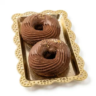 Two chocolate ring pastries with milk chocolate coating and hazelnut pieces on a decorative tray
