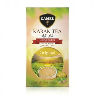 A professional studio photograph featuring a single box of Camel Karak Tea Unsweetened Instant Premix, centered on a solid white background. The box displays the yellow-green packaging with a picture of a steaming cup of tea and a landscape. All text and the camel logo are clearly visible, with no price tags present.