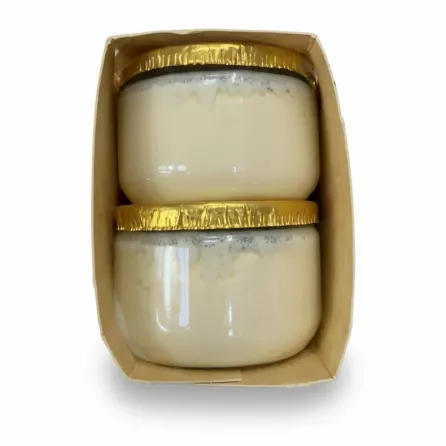 Two glass pots of vanilla cream inside packaging held in hand