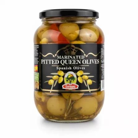Jar of marinated pitted queen olives with herbs and red peppers