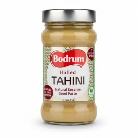 Glass jar of Bodrum Hulled Tahini with silver lid on white background