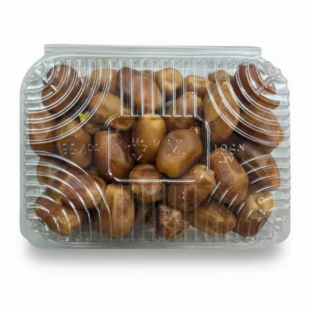Hand holding clear plastic tray of fresh Zahedi dates in store aisle