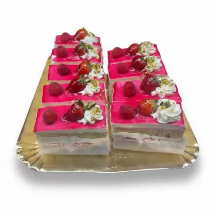 Tray of multiple Mixed Berry Celebration Cake slices decorated with fresh berries, whipped cream and pistachios