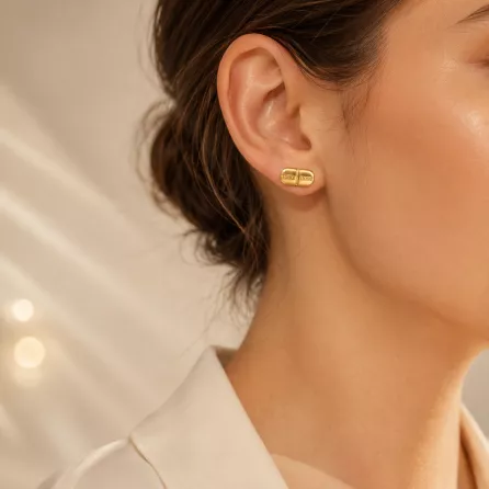 Model wearing 14K gold plated Daily Dosage Pill Stud Earrings against a soft abstract light background, highlighting the unique capsule shaped stud earrings.