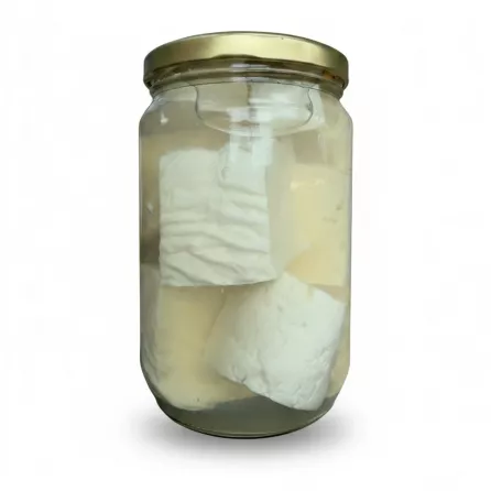 Side view of white cheese pieces immersed in clear brine in jar