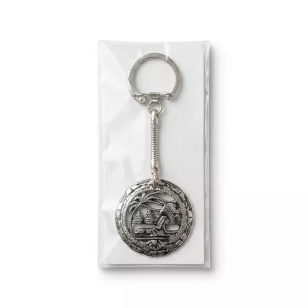 Enhanced Hand holding a silver keyring with palm tree and building motif in packaging