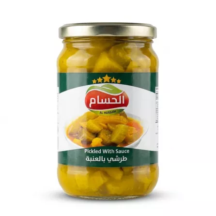 A 1:1 e-commerce photo of a glass jar containing Al Hussam Pickled With Sauce, isolated on a pure white background. The jar is centered and features a clear green and white label with the brand name 'Al Hussam' and five gold stars, an image of the pickled contents, and the product title in both English and Arabic.