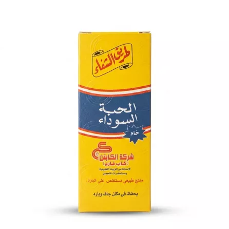 A professional studio photo of a bright yellow cardboard box for El Captain Black Seed Oil Cold Pressed Raw. The box is centered on a clean white background, showing extensive Arabic text, brand logos, and texture, all in sharp focus.