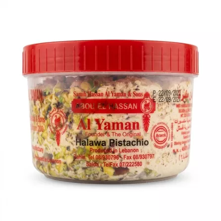 A 454g clear plastic tub of Al Yaman Halawa with whole pistachios from Lebanon, presented as a professional e-commerce product photo on a clean white background. The red lid is visible at the top. The label is sharp, clearly showing all text and branding, including "Al Yaman Halawa Pistachio," "Produced in Lebanon," and contact details. PRODUCT TITLE: Al Yaman Halawa Pistachio PRODUCT: A professional, studio-quality e-commerce photograph of the Al Yaman Halawa Pistachio 454g tub, as shown in image_0.png, but centered and filling approximately 85% of the square (1:1 aspect ratio) frame. All elements of the messy store background (floors, feet, hands, shelves, products, price tags) are completely removed, replaced by a flawless, seamless pure white studio background. The product, a clear plastic tub with a red ribbed screw-top lid, is isolated. The contents, a dense, creamy-looking Halawa mixture densely studded with whole, rich green pistachios, are perfectly clear and sharp, with all surface imperfections on the plastic tub (fingerprints, dust, etc.) digitally cleaned. The front label from image_0.png is kept, but rendered with razor-sharp clarity, ensuring every detail is perfectly legible, including: the title "Al Yaman" in large red script with "Founder & The Original" below it; "Halawa Pistachio" clearly written; the Producer "Produced in Lebanon" and contact numbers ("Tel 08/930796", "Tel/Fax 07/222580"); and other branding logos ("ACERTA" certification, "The Original" with a chef-like icon). The red lid at the top is pristine. The composition is head-on. The lighting is soft and even professional studio quality, designed to make the pistachios pop and make all text perfectly readable. The product casts a very subtle, soft, symmetrical contact shadow directly beneath it, balanced on both sides, grounding it without being obtrusive. All specific text, numbers, and facts from the label in image_0.png are preserved exactly, just made clearer. All visible labels, price stickers, and tags are removed from the background. The final image is sharp-focus throughout.
