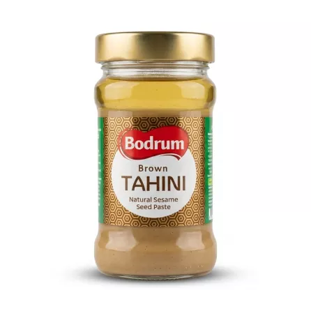 Enhanced Hand holding a jar of Bodrum Brown Tahini with front label visible
