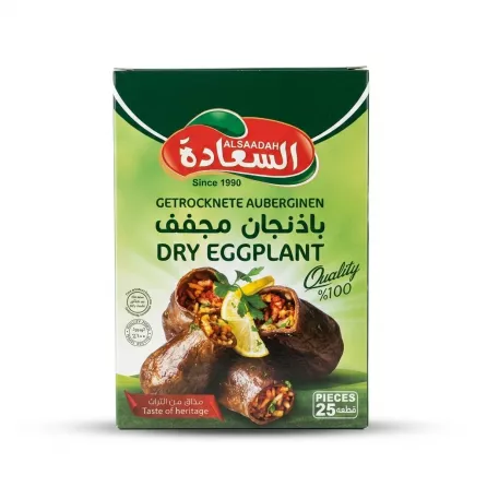 A professional studio photograph of the Alsaadah Dry Eggplant retail box, centered against a clean white background. The box, which is in sharp focus, displays the complete green and white packaging design with the red and white Alsaadah logo in English and Arabic. Text reads: "Since 1990," "GETROCKNETE AUBERGINEN," "بَاذِنْجَانٌ مُجَفَّفٌ," "DRY EGGPLANT," and "Quality %100." A realistic image of stuffed and cooked aubergine pieces is prominent, along with a 'PIECES 25' label. A soft, symmetric shadow is cast beneath the product. PROD-URL: www.example.com/dry-eggplant-pack-alsaadah-25