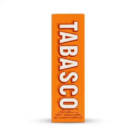 A professional studio photograph against a clean white background, showing the side of an orange Tabasco Classic Pepper Sauce box with the large white "TABASCO" logo and text details. The box is centered with soft, even shadowing.