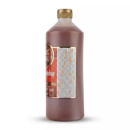 A side-view studio photograph of a 1L Heera Tomato Ketchup bottle with a gold cap, centered against a seamless white background, displaying the full list of ingredients and nutritional information on the back label.