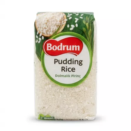 A 1kg package of Bodrum Pudding Rice, specifically labeled 'Dolmalık Pirinç', is shown in a clean, professional photo. The packaging features a clear window at the bottom revealing the uncooked short-grain rice, and includes green leaves, a bowl of cooked rice, and the Bodrum brand logo. PRODUCT TITLE: Bodrum Pudding Rice - Halal, Gluten-Free 1kg