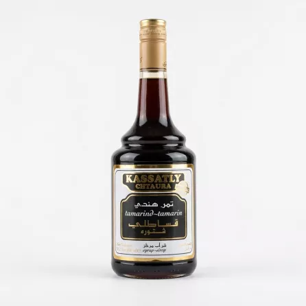 A 600ml glass bottle of Kassatly Chtaura Tamarind Syrup with its black and gold label, containing a dark amber liquid and sealed with a gold screw cap, isolated on a plain white background.