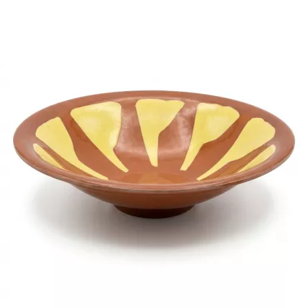 Enhanced Hand holding a decorative brown and yellow ceramic shallow bowl, side view