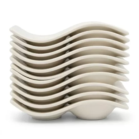A stacked set of eight distinctive S-shaped, cream-colored ceramic saucers from a coffee set, shown isolated against a pure white background. The stacked saucers form a continuous wavy profile, highlighting their unique curved design.