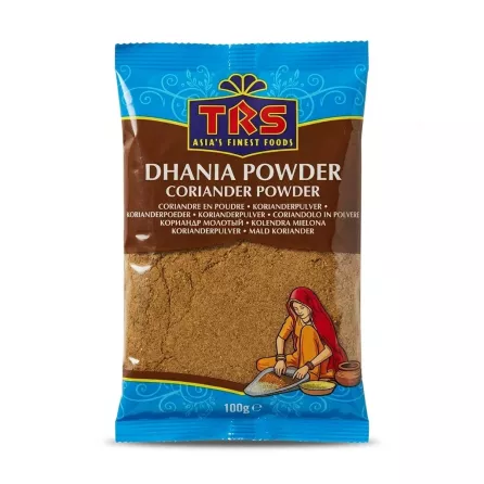 A 100g retail package of TRS Dhania (Coriander) Powder, with branding and an image of a woman grinding spices, shown against a solid white background.