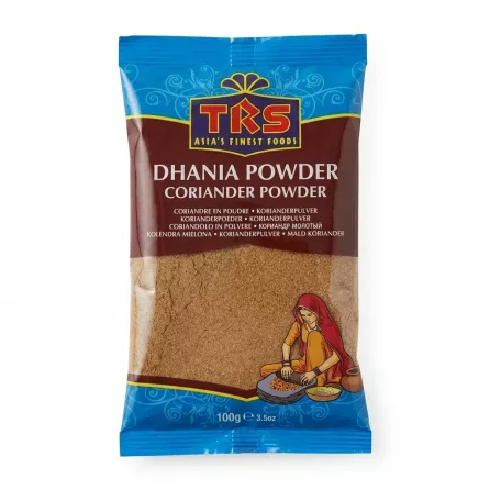 A 100g retail pouch of TRS Dhania Coriander Powder with an illustration of a woman grinding spices, isolated against a clean white background.