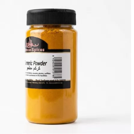 A clear glass jar filled with vibrant yellow Moroccan Spices Turmeric Powder. The jar features a label with a barcode and Arabic text, and is shown against a clean, solid white background with professional lighting.