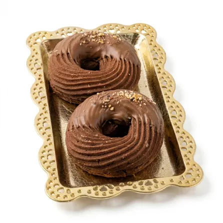 Two chocolate ring pastries with milk chocolate coating and hazelnut pieces on a decorative tray