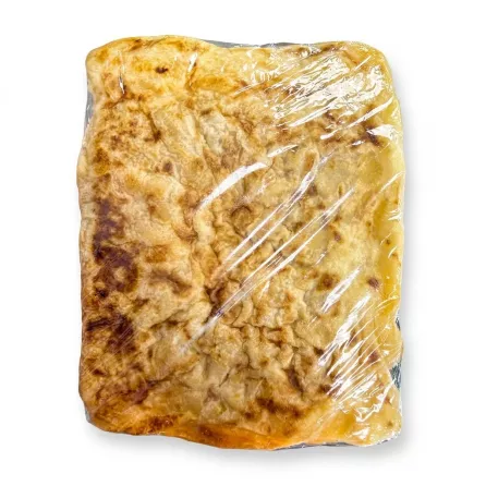 Hand holding a packaged plain msemen flatbread with a golden, flaky surface