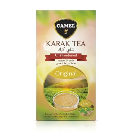 A professional studio photograph featuring a single box of Camel Karak Tea Unsweetened Instant Premix, centered on a solid white background. The box displays the yellow-green packaging with a picture of a steaming cup of tea and a landscape. All text and the camel logo are clearly visible, with no price tags present.