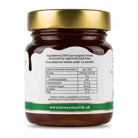 A clean, studio photograph of the back label of Honeyman UK Organic Forest Honey, showing ingredients and detailed nutritional information for 100g, including energy, fats, carbohydrates, and protein, against a pure white background. The jar is centered, featuring a gold lid and a green-banded label.