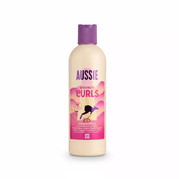 Aussie Bouncy Curls Shampoo bottle with purple cap and pink label held in hand