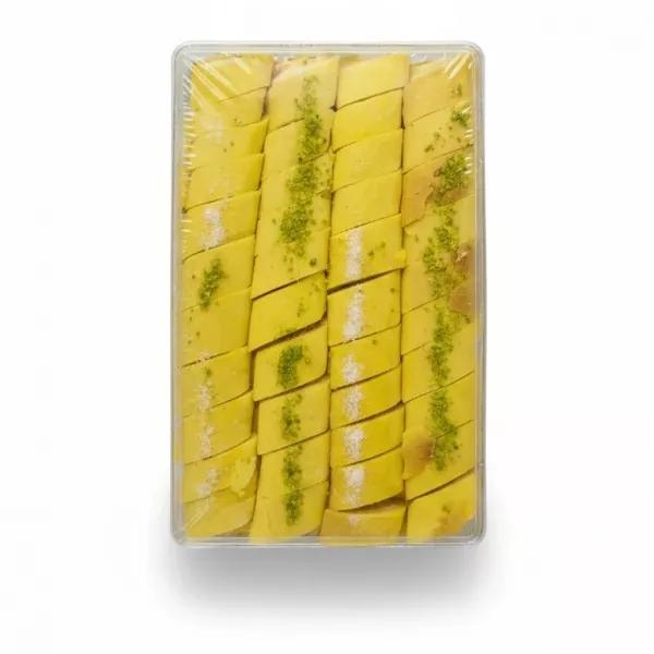Clear plastic pack of yellow saffron-based Kak Candy with visible sliced nut pieces inside