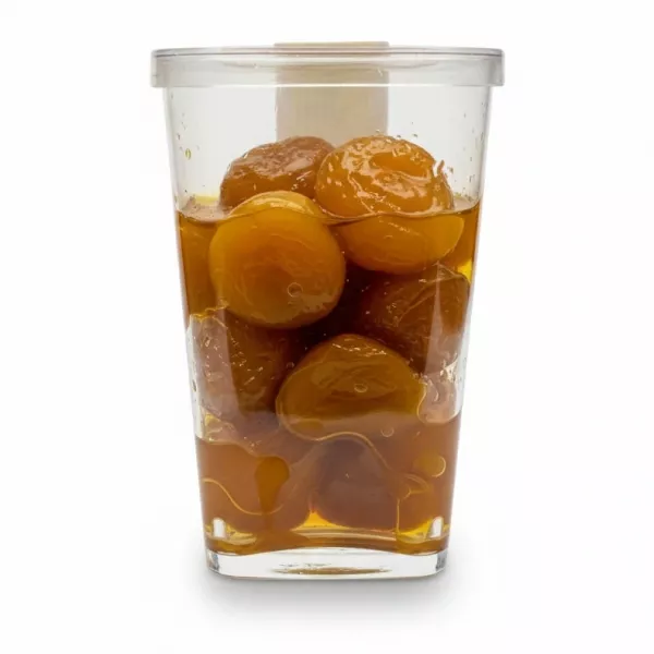 Container of golden plums in syrup held in hand
