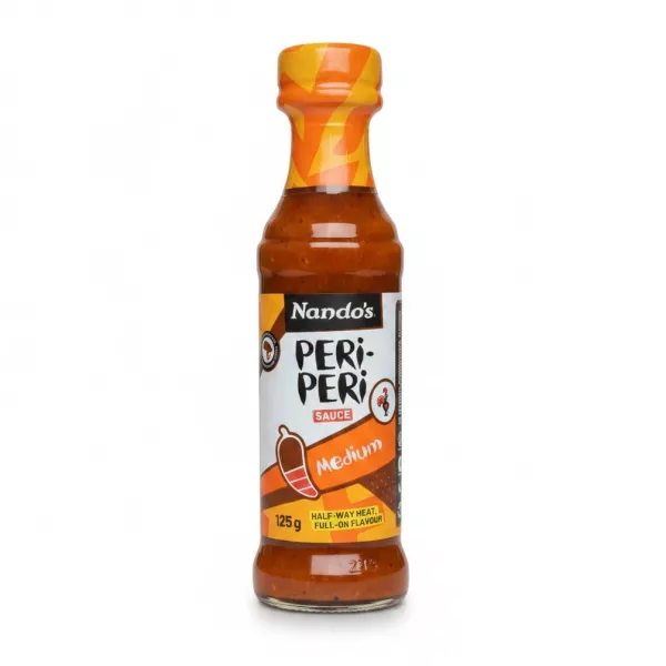 Bottle of Nando's Peri-Peri Medium Sauce held in hand showing front label