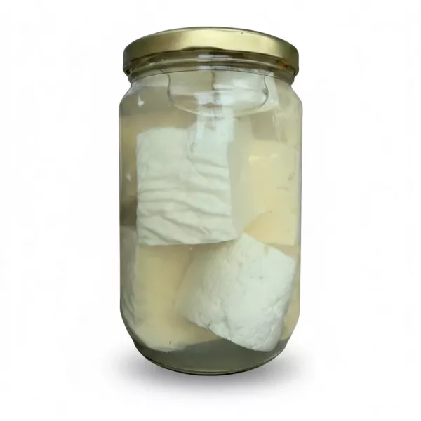 Side view of white cheese pieces immersed in clear brine in jar