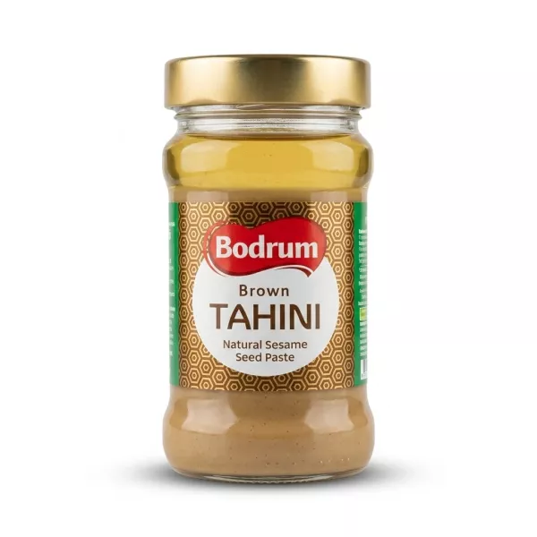 Enhanced Hand holding a jar of Bodrum Brown Tahini with front label visible