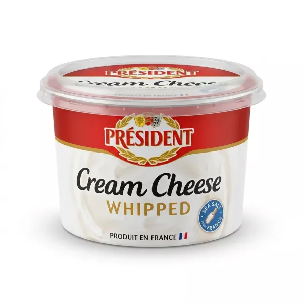 Enhanced Hand holding Président Whipped Cream Cheese tub in a grocery store