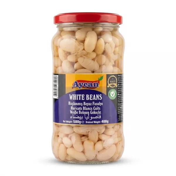 A 580g glass jar of Aycan white beans, featuring a red lid and clear glass. The blue label displays "Aycan," "WHITE BEANS," and translations in several languages, set against a seamless white background with a soft shadow.