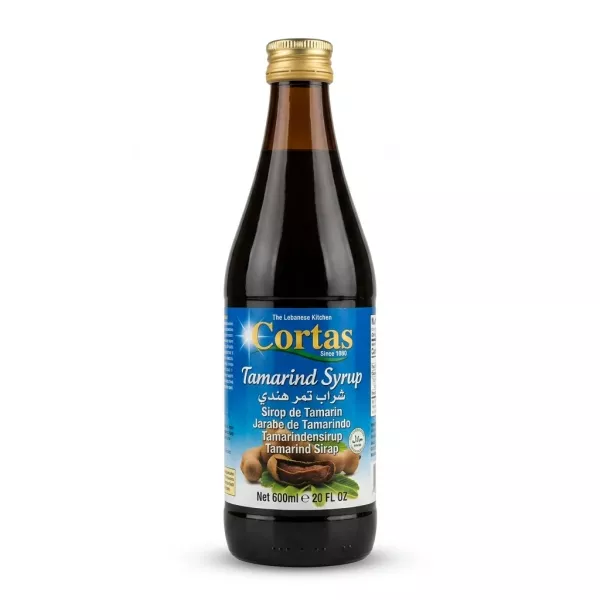 Enhanced Cortas Tamarind Syrup 600ml bottle with gold cap, held in hand in a grocery store aisle
